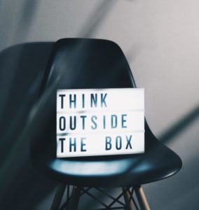 A marque sign sits on a modern black chair. The sign reads, "Think outside the box."